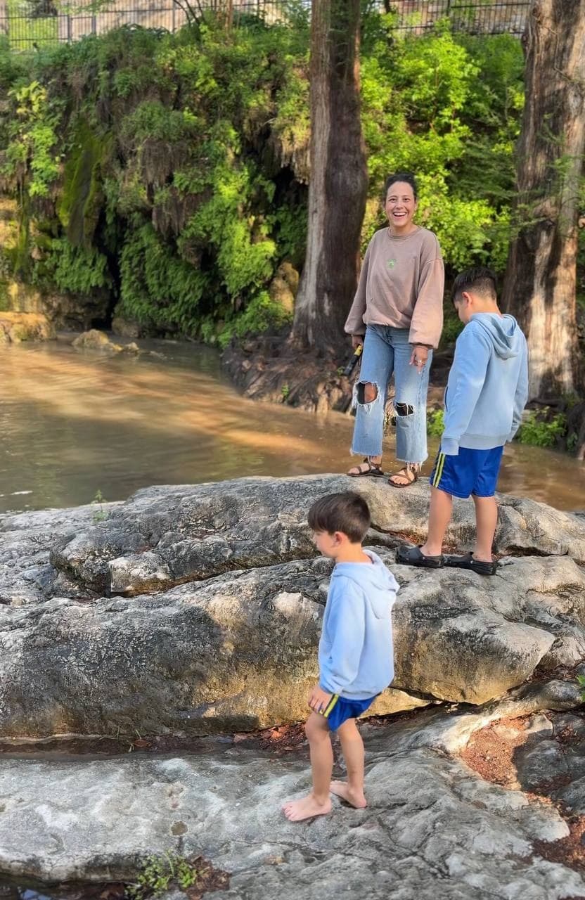Daniela and her children exploring rocks near a creek